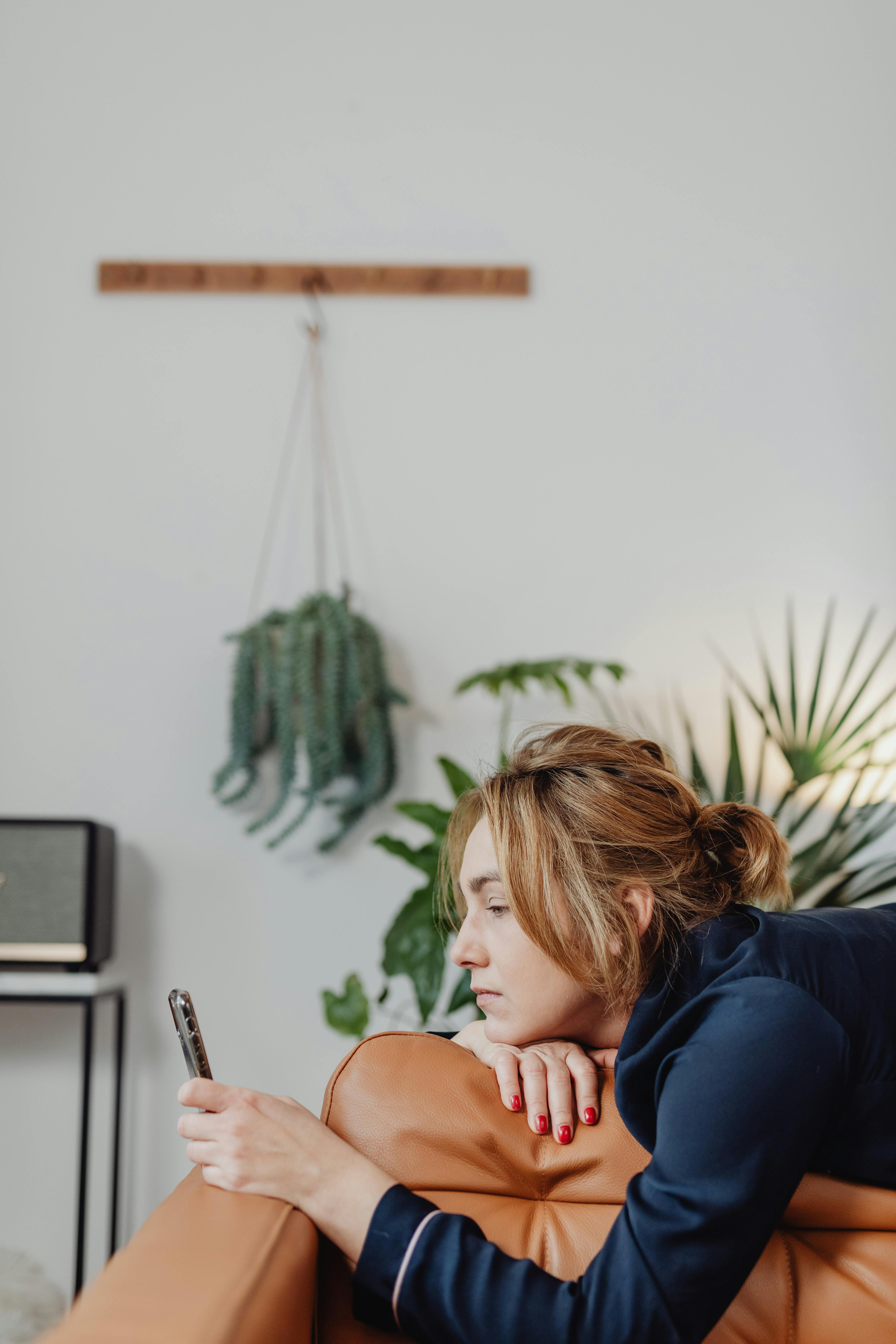 Kobieta leżąca na kanapie, patrzy na telefon | Źródło: Pexels